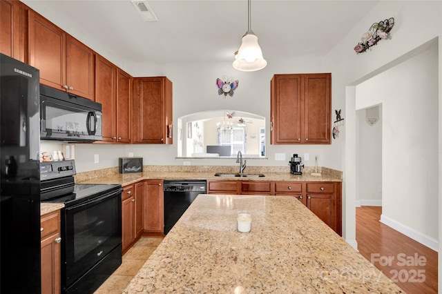 kitchen with light stone counters, sink, black appliances, pendant lighting, and a chandelier