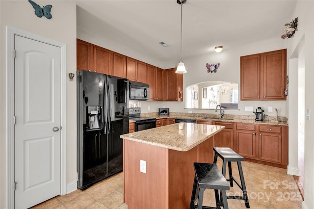 kitchen featuring black appliances, a kitchen breakfast bar, sink, hanging light fixtures, and a kitchen island