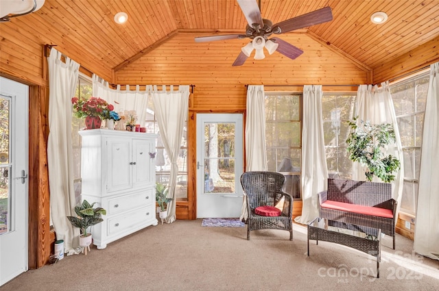 living area featuring carpet flooring, high vaulted ceiling, ceiling fan, and wooden walls