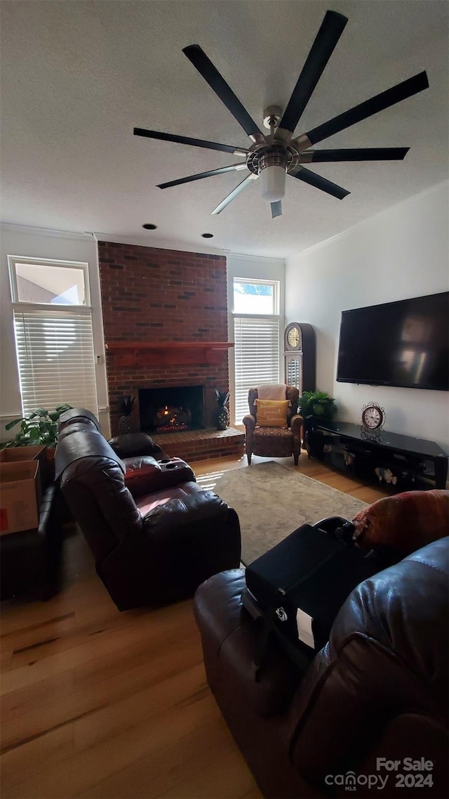 living room with ceiling fan, hardwood / wood-style floors, and a brick fireplace