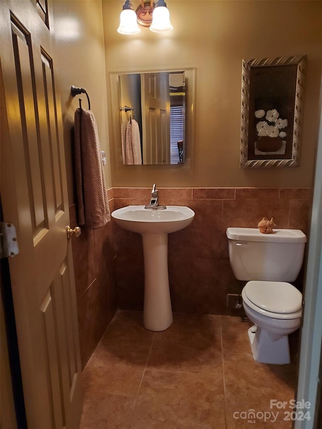 bathroom featuring toilet, tile patterned floors, and tile walls