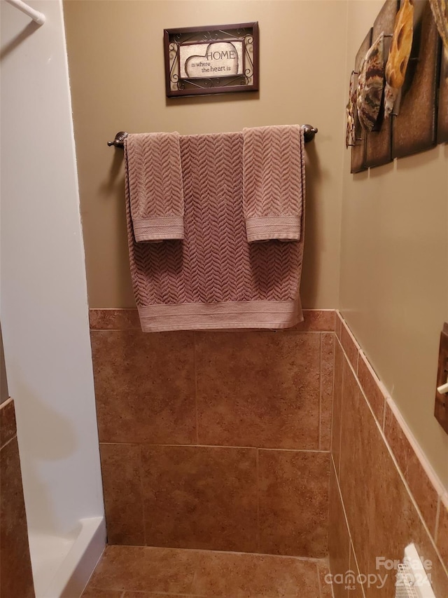 bathroom featuring walk in shower and tile walls