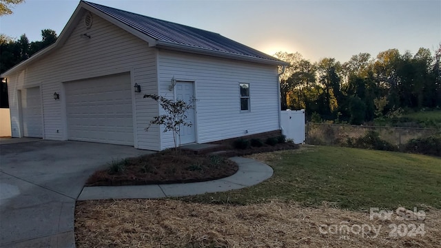 property exterior at dusk featuring a lawn, an outdoor structure, and a garage