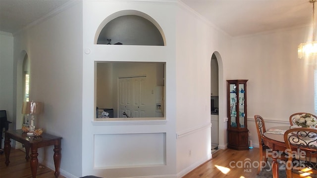 dining area with ornamental molding, arched walkways, and wood finished floors