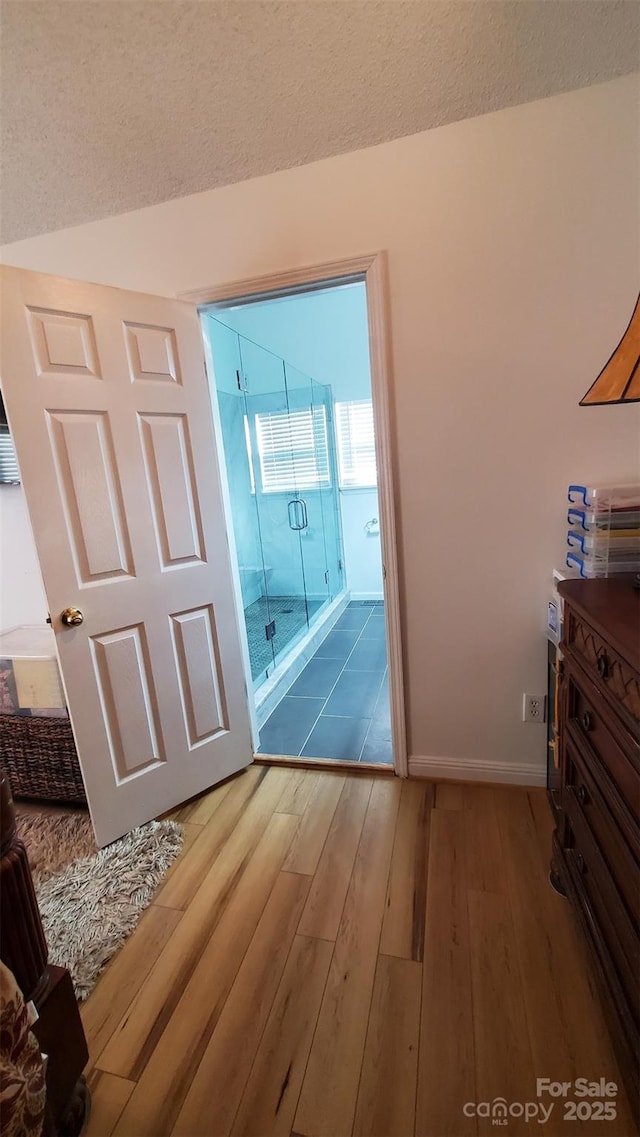interior space featuring baseboards, a textured ceiling, and wood finished floors