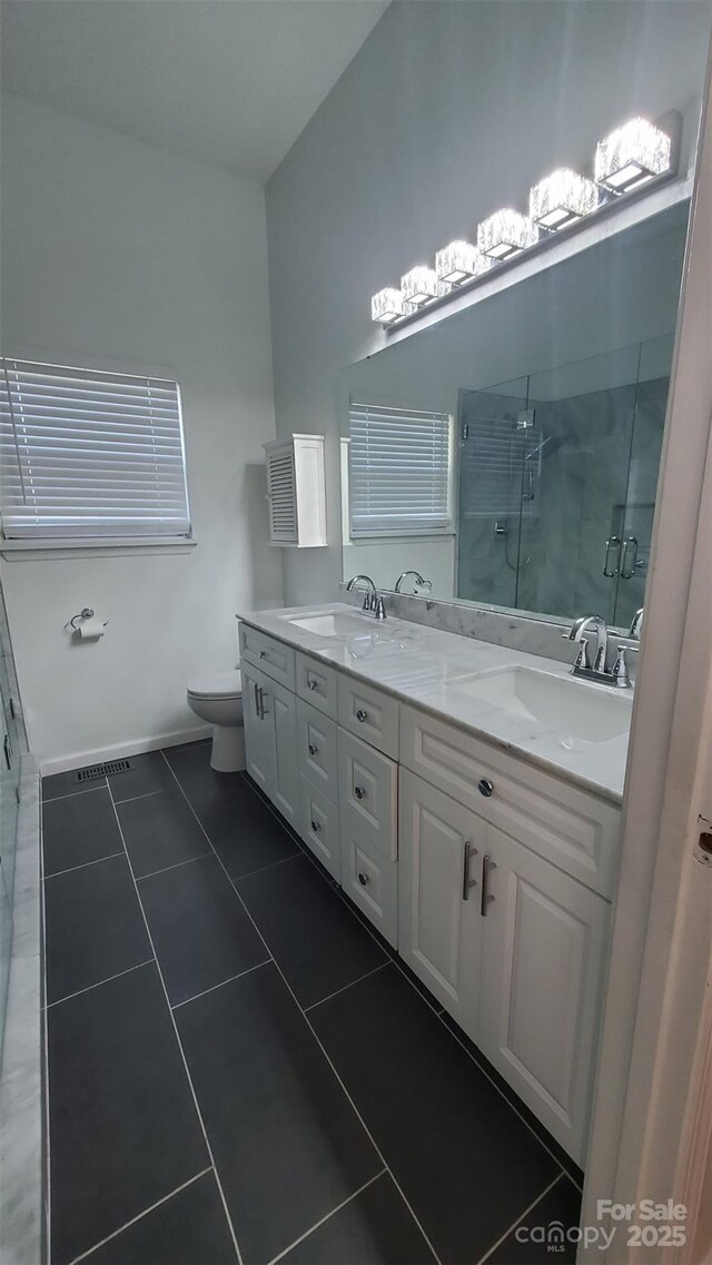 bathroom featuring a stall shower, double vanity, a sink, and tile patterned floors