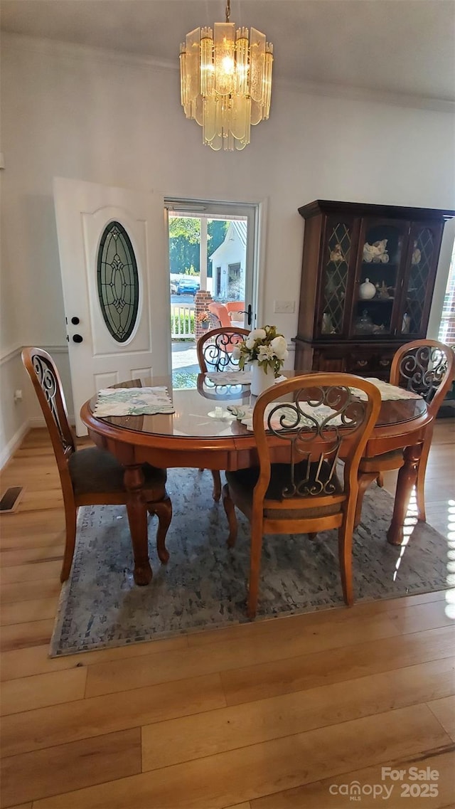 dining room featuring visible vents, wood finished floors, and a notable chandelier