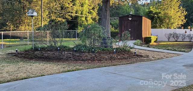 view of yard featuring fence, an outdoor structure, and a storage shed