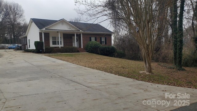view of front facade featuring a front lawn, brick siding, and concrete driveway