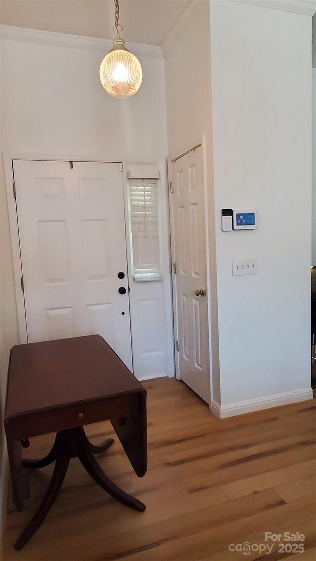 foyer entrance with baseboards, crown molding, and light wood-style floors