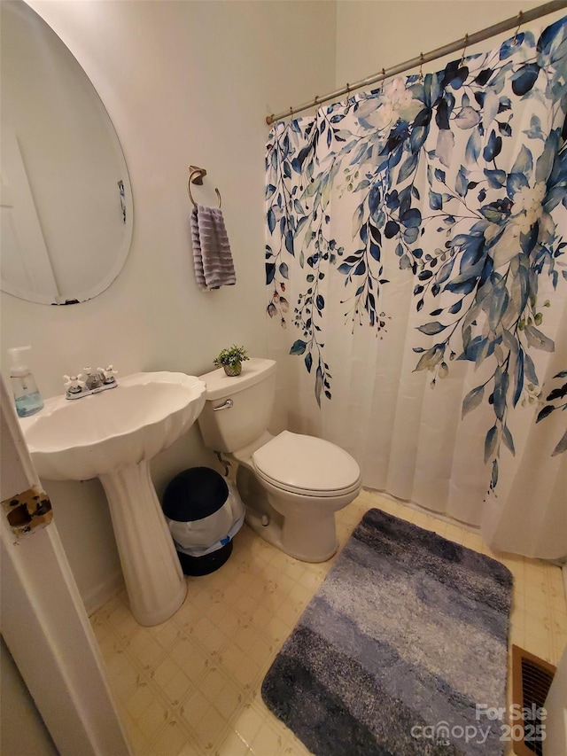 bathroom with tile patterned floors, toilet, and curtained shower