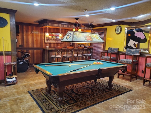 rec room with a dry bar, a textured ceiling, wood walls, and billiards