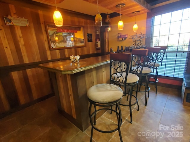 bar with tile patterned flooring, wood walls, and bar