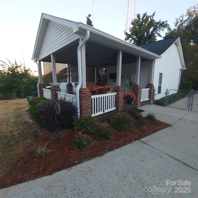 view of property exterior featuring a gate, a porch, and brick siding
