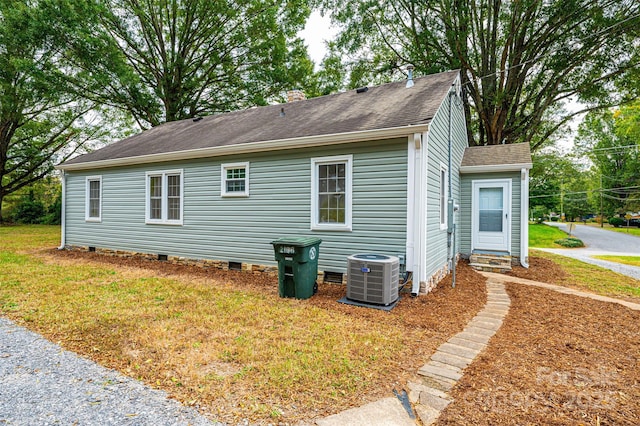 view of side of property with central air condition unit and a yard