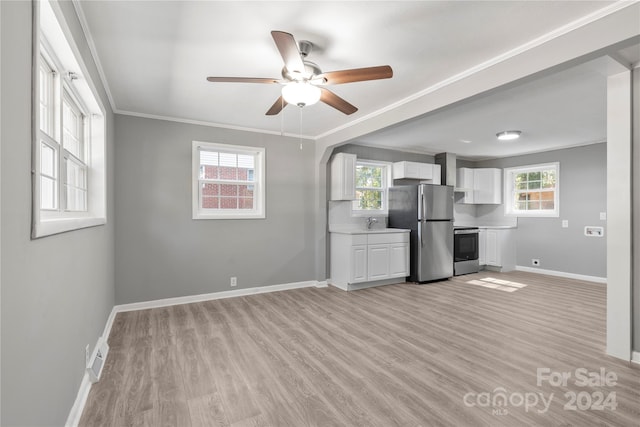 kitchen with light wood-type flooring, appliances with stainless steel finishes, white cabinetry, and a healthy amount of sunlight