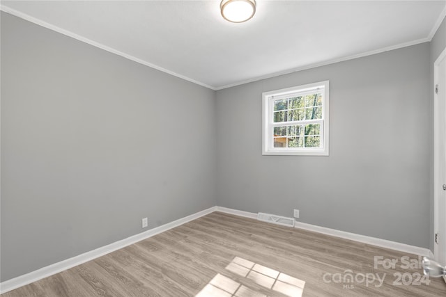 empty room featuring ornamental molding and light hardwood / wood-style floors