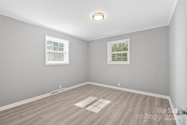 empty room featuring ornamental molding and light wood-type flooring