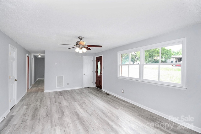 unfurnished room with a textured ceiling, ceiling fan, and light hardwood / wood-style flooring