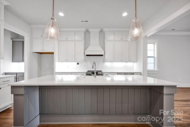 kitchen featuring custom exhaust hood, hanging light fixtures, dark hardwood / wood-style floors, and a spacious island