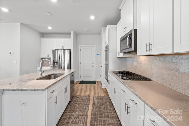 kitchen featuring white cabinets, appliances with stainless steel finishes, and an island with sink