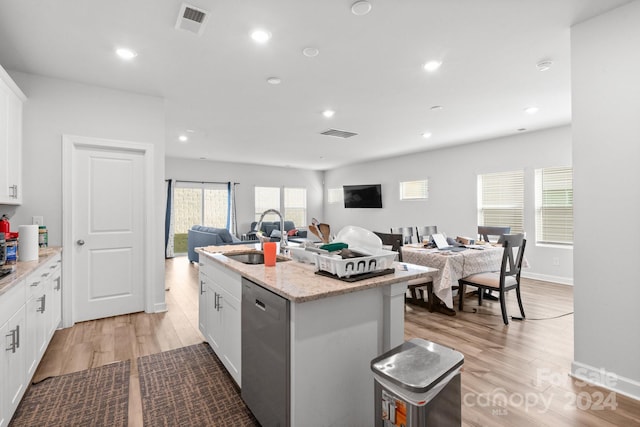 kitchen with a center island with sink, sink, white cabinets, stainless steel dishwasher, and light hardwood / wood-style flooring