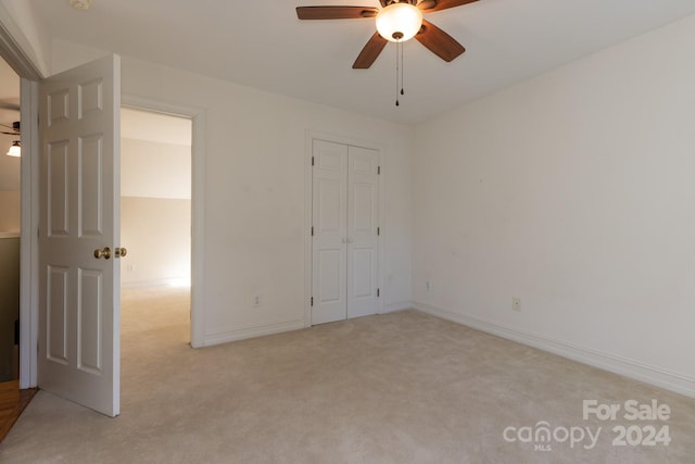 unfurnished bedroom featuring a closet, light colored carpet, and ceiling fan