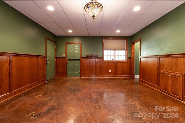 spare room with wood walls and a drop ceiling