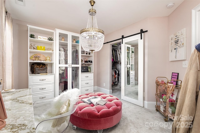 spacious closet featuring light carpet, a notable chandelier, and a barn door