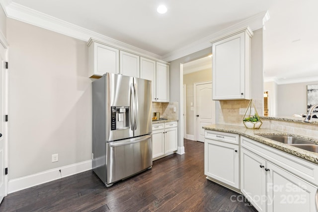 kitchen with white cabinetry, sink, light stone counters, and stainless steel fridge