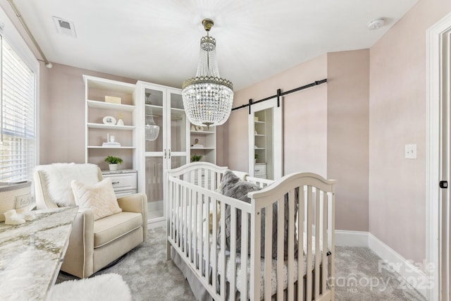 carpeted bedroom featuring a barn door and a chandelier