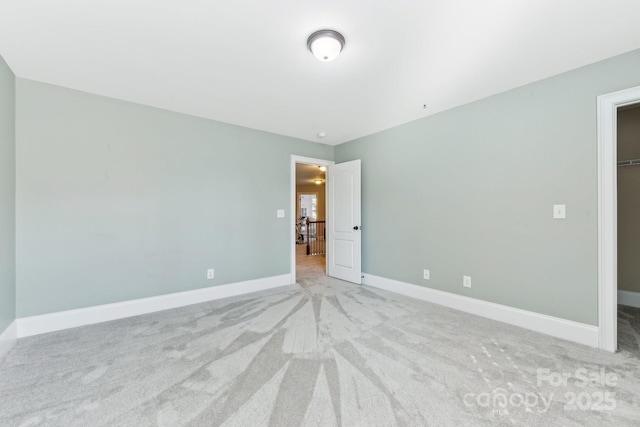 unfurnished bedroom featuring a walk in closet, light colored carpet, and a closet