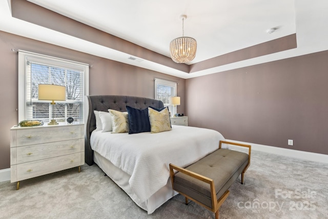 bedroom with an inviting chandelier, a tray ceiling, and light carpet