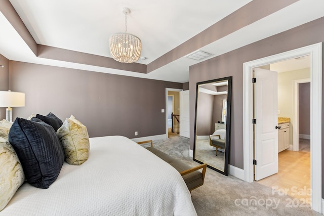 carpeted bedroom featuring a raised ceiling and a chandelier