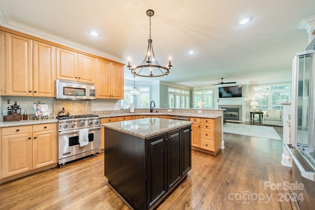 kitchen with light brown cabinetry, pendant lighting, a kitchen island, and stainless steel appliances