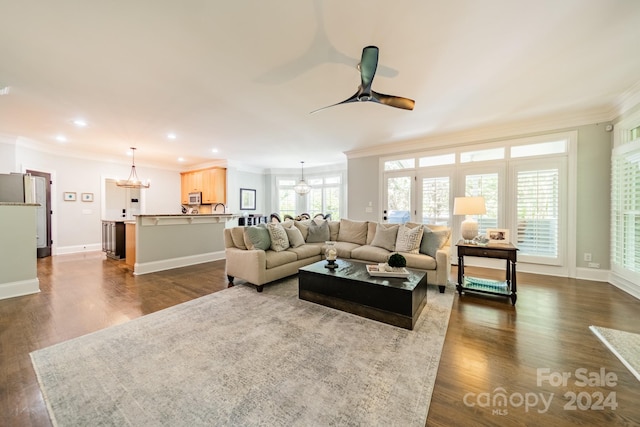 living room featuring ornamental molding, dark wood-type flooring, and ceiling fan with notable chandelier