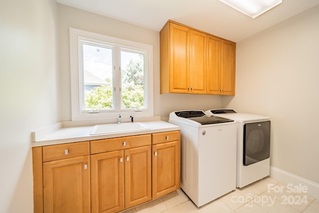 laundry room with light tile patterned floors, cabinets, sink, and washing machine and clothes dryer