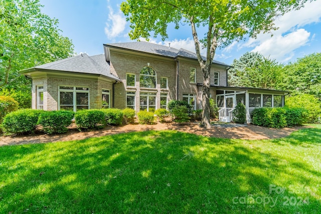 rear view of house with a lawn and a sunroom