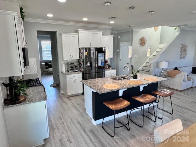 kitchen featuring a breakfast bar, light stone countertops, sink, and white cabinets