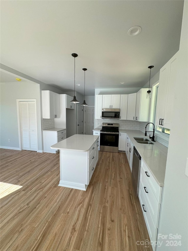 kitchen with decorative backsplash, stainless steel appliances, sink, a center island, and white cabinetry