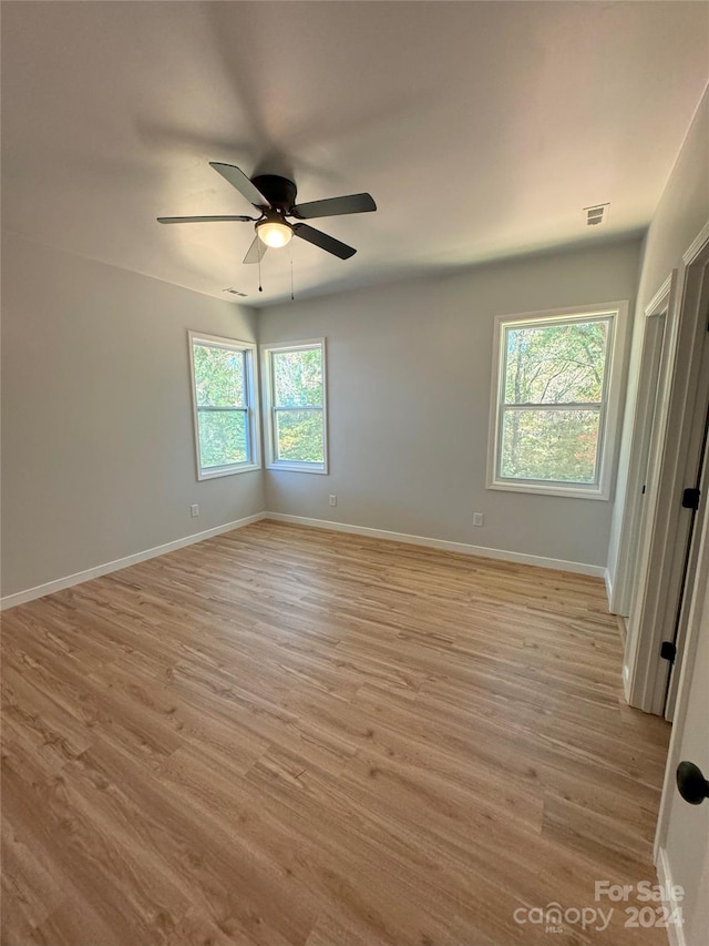 spare room with ceiling fan, plenty of natural light, and light wood-type flooring