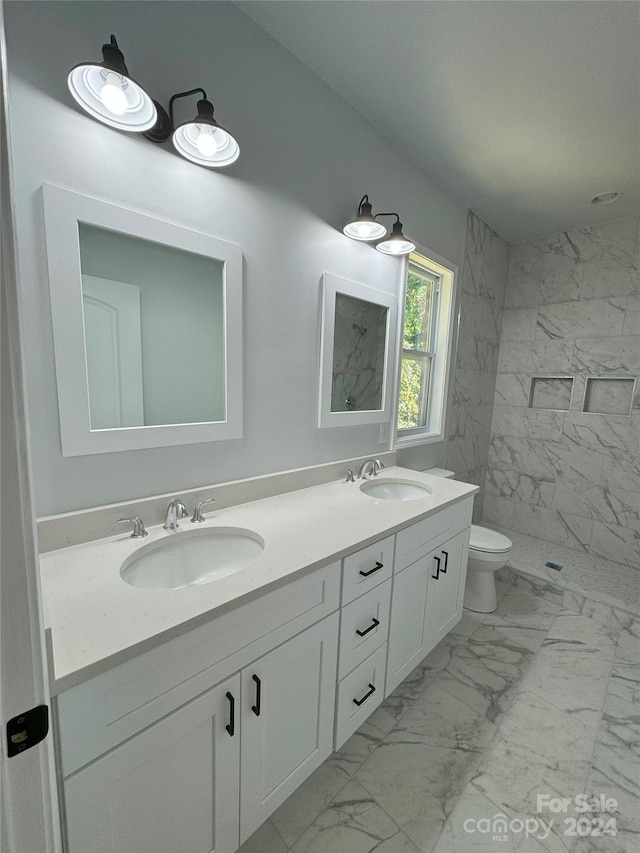 bathroom with vanity, toilet, and tiled shower