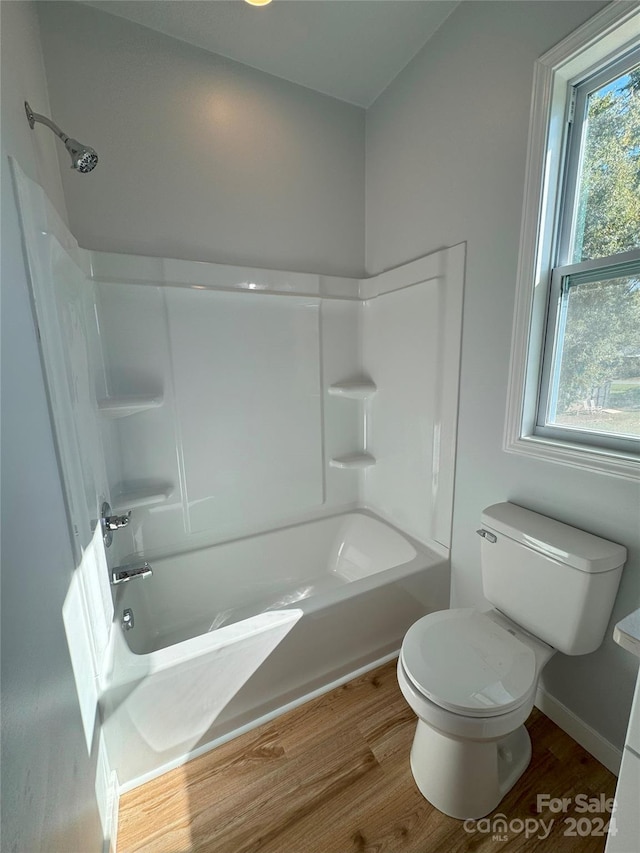 bathroom featuring toilet, hardwood / wood-style flooring, and shower / washtub combination