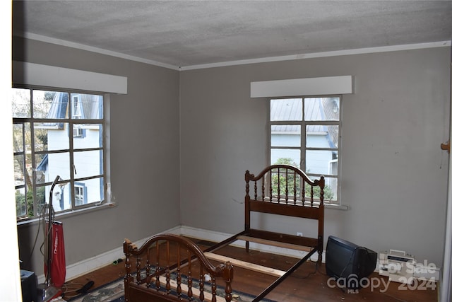 bedroom with multiple windows, a textured ceiling, hardwood / wood-style flooring, and ornamental molding