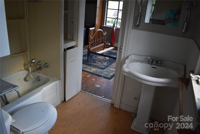 bathroom with hardwood / wood-style flooring, tub / shower combination, and toilet