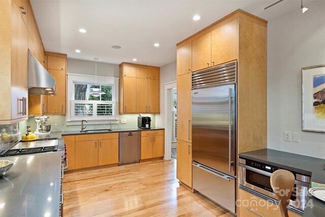 kitchen featuring extractor fan, stainless steel appliances, light brown cabinetry, and light hardwood / wood-style flooring