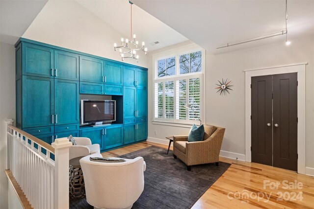 living room with high vaulted ceiling, a chandelier, and hardwood / wood-style flooring