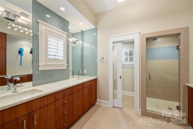 bathroom featuring a wealth of natural light, tile patterned flooring, and a shower with shower door