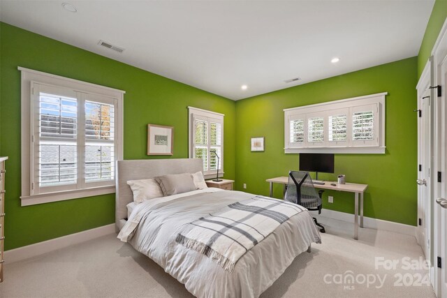 bedroom with multiple windows and light carpet