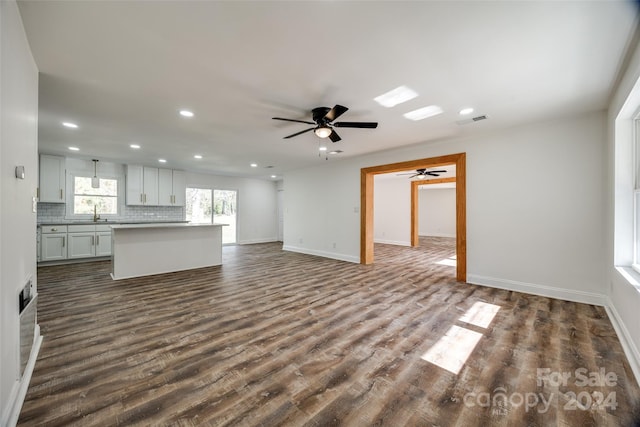 unfurnished living room with ceiling fan, dark hardwood / wood-style flooring, and sink